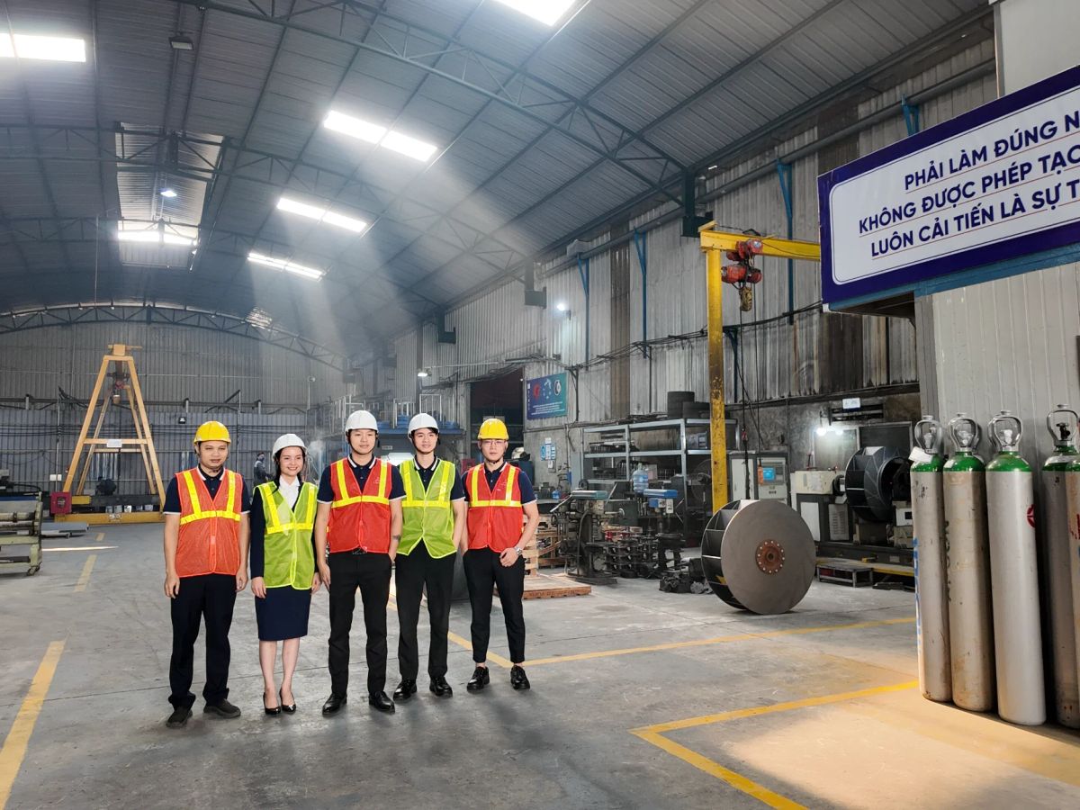 Group of individuals in safety gear inside a workshop.