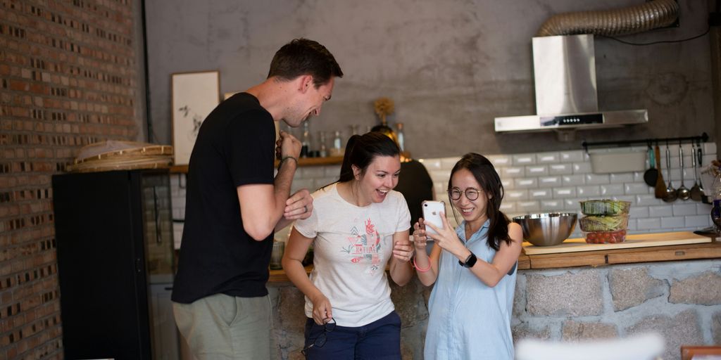 woman wearing white crew-neck shirt looking at smartphone friends