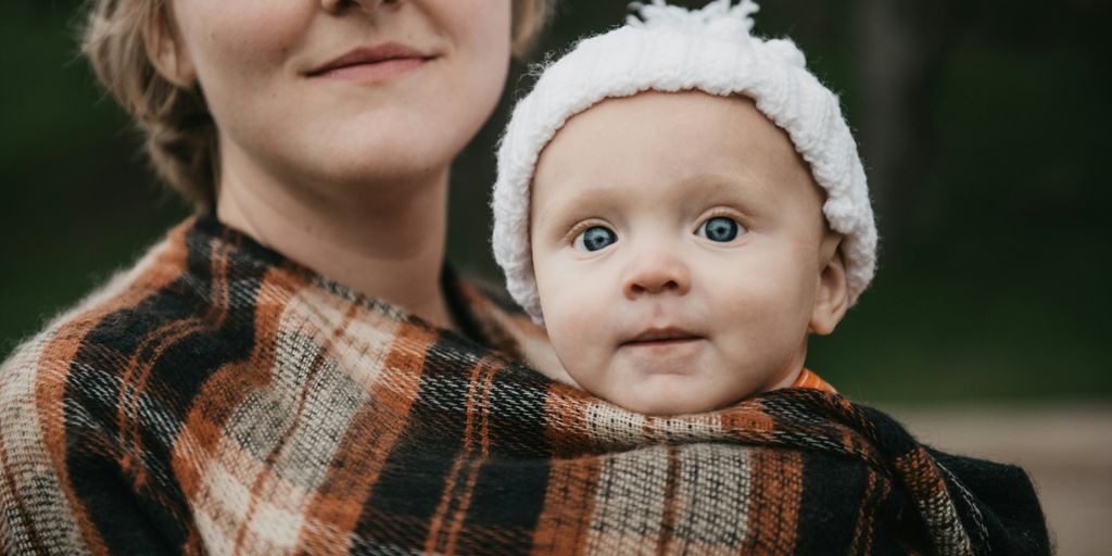 a woman holding a baby wrapped in a blanket