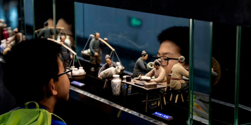 boy looking at human figurines in glass case