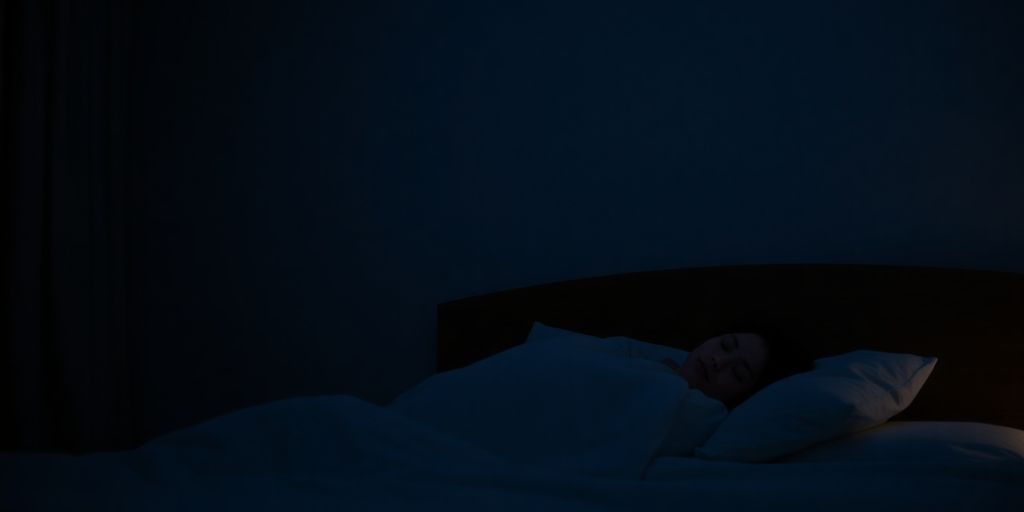 Person peacefully sleeping with serene bedroom.