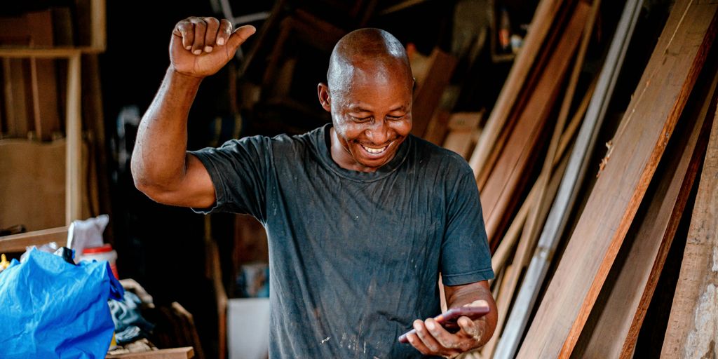 a man smiles while looking at his cell phone