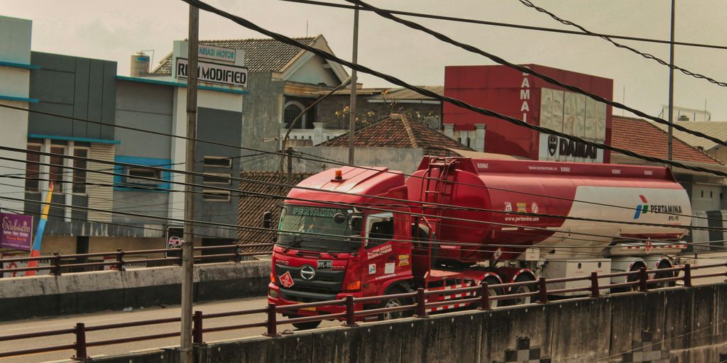 a red truck driving down a street next to a tall building