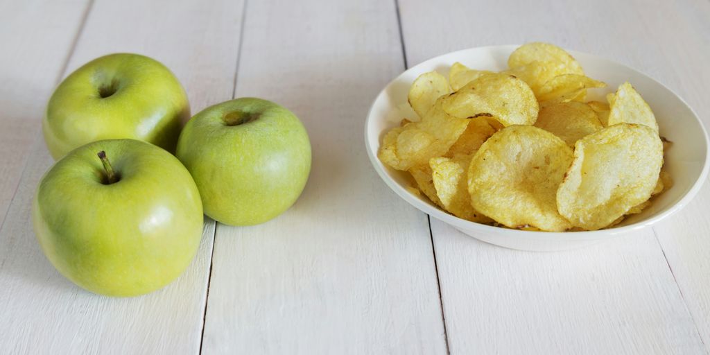 a bowl of chips next to a bowl of apples