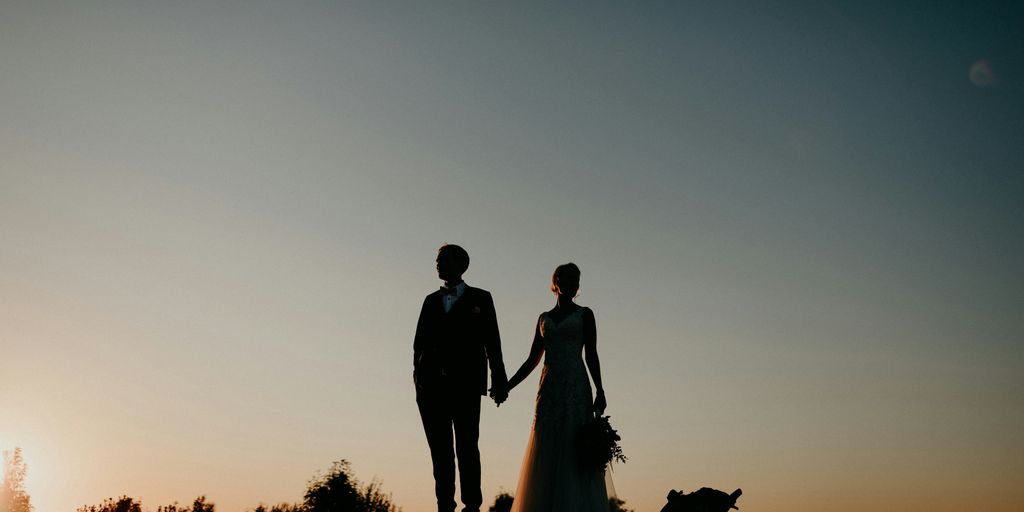 A bride and groom holding hands at sunset