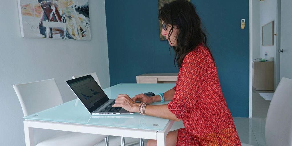 Woman works on laptop at a table.