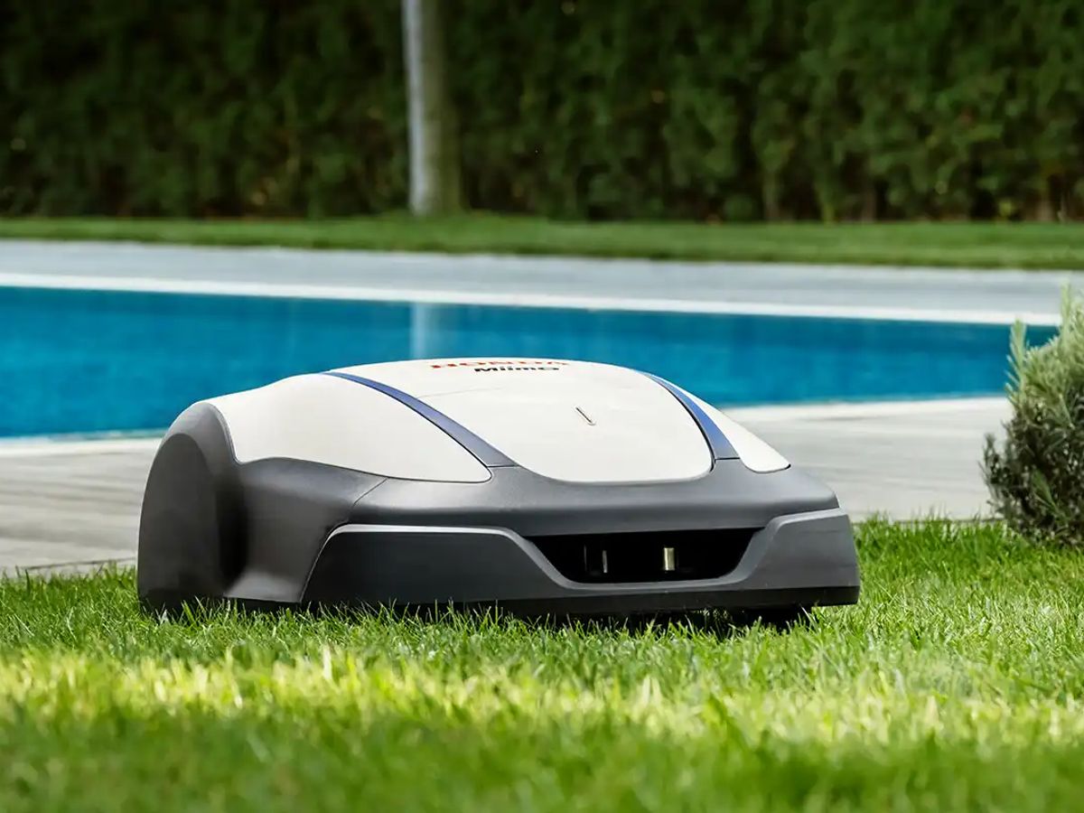 Robot mower operating on grass near a pool.