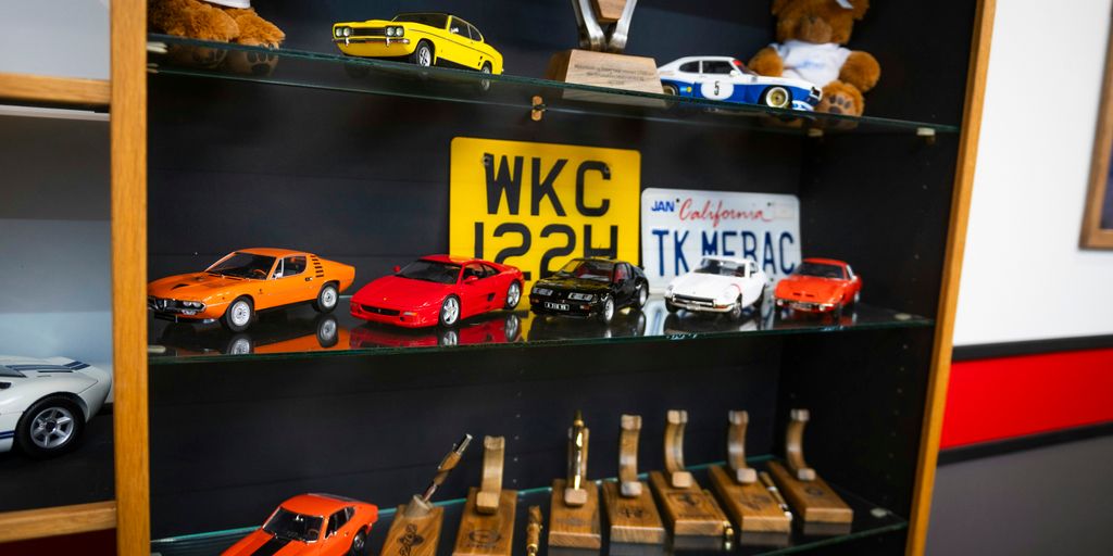 A shelf displays car models, trophies, and other items.