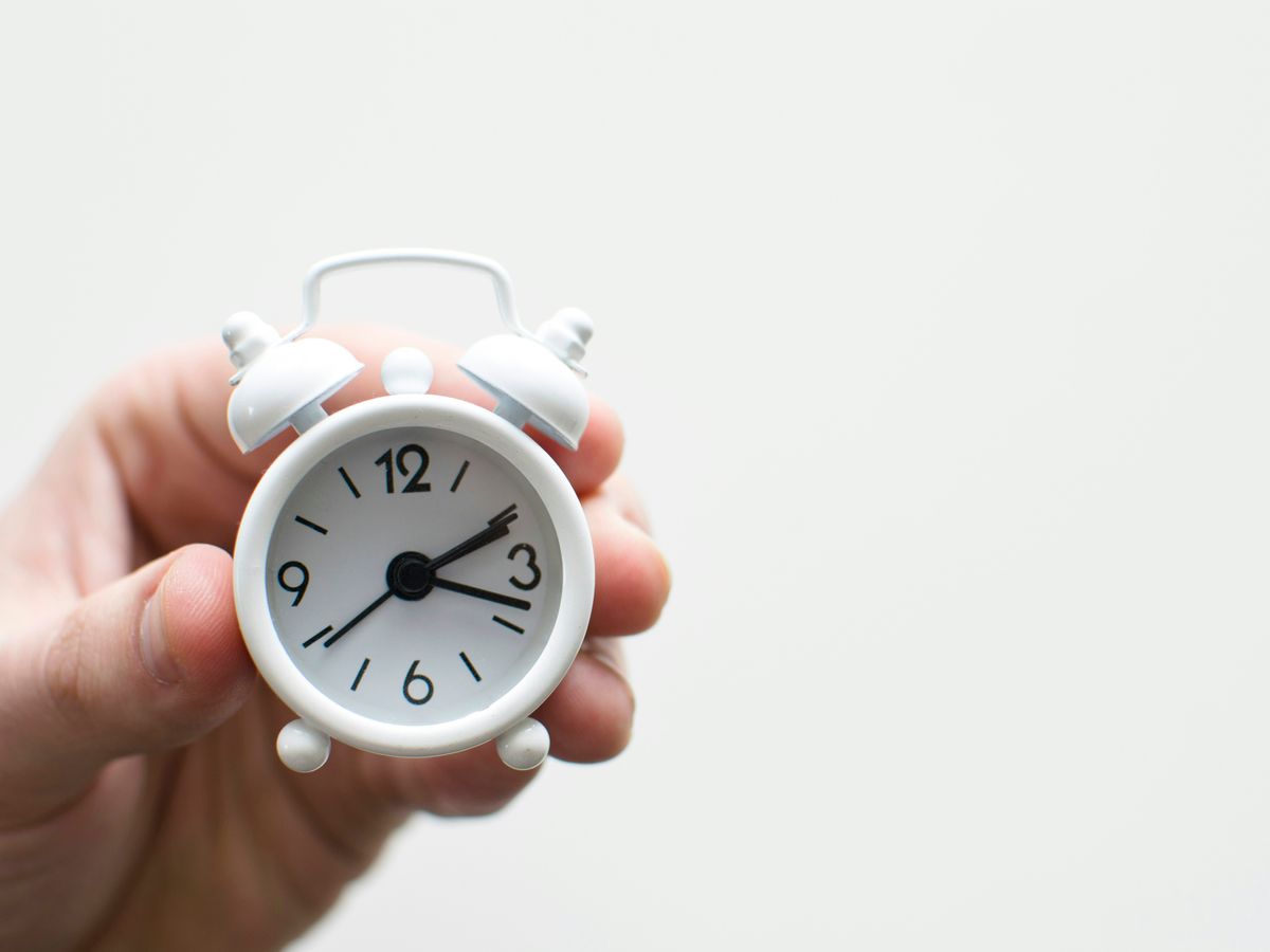 person holding white mini bell alarmclock