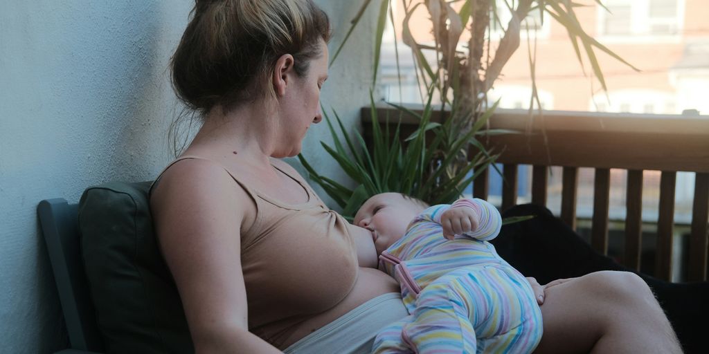 a woman sitting on a bench holding a baby