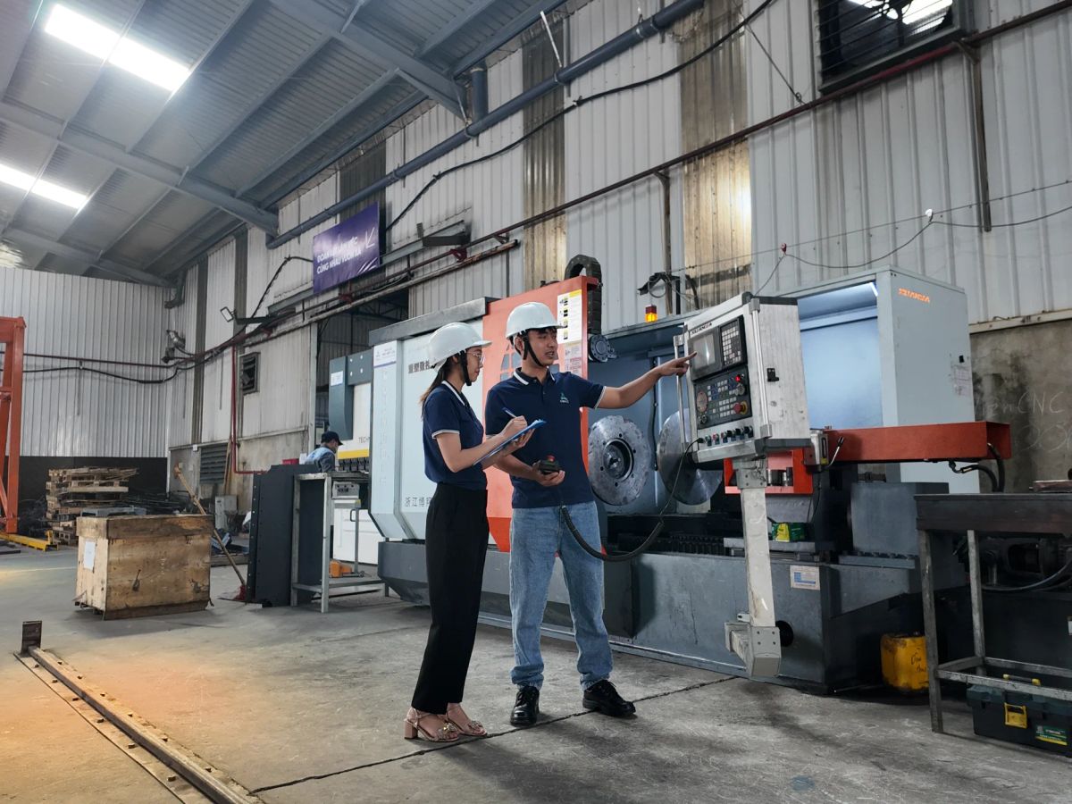 Two individuals discuss equipment in a manufacturing facility.