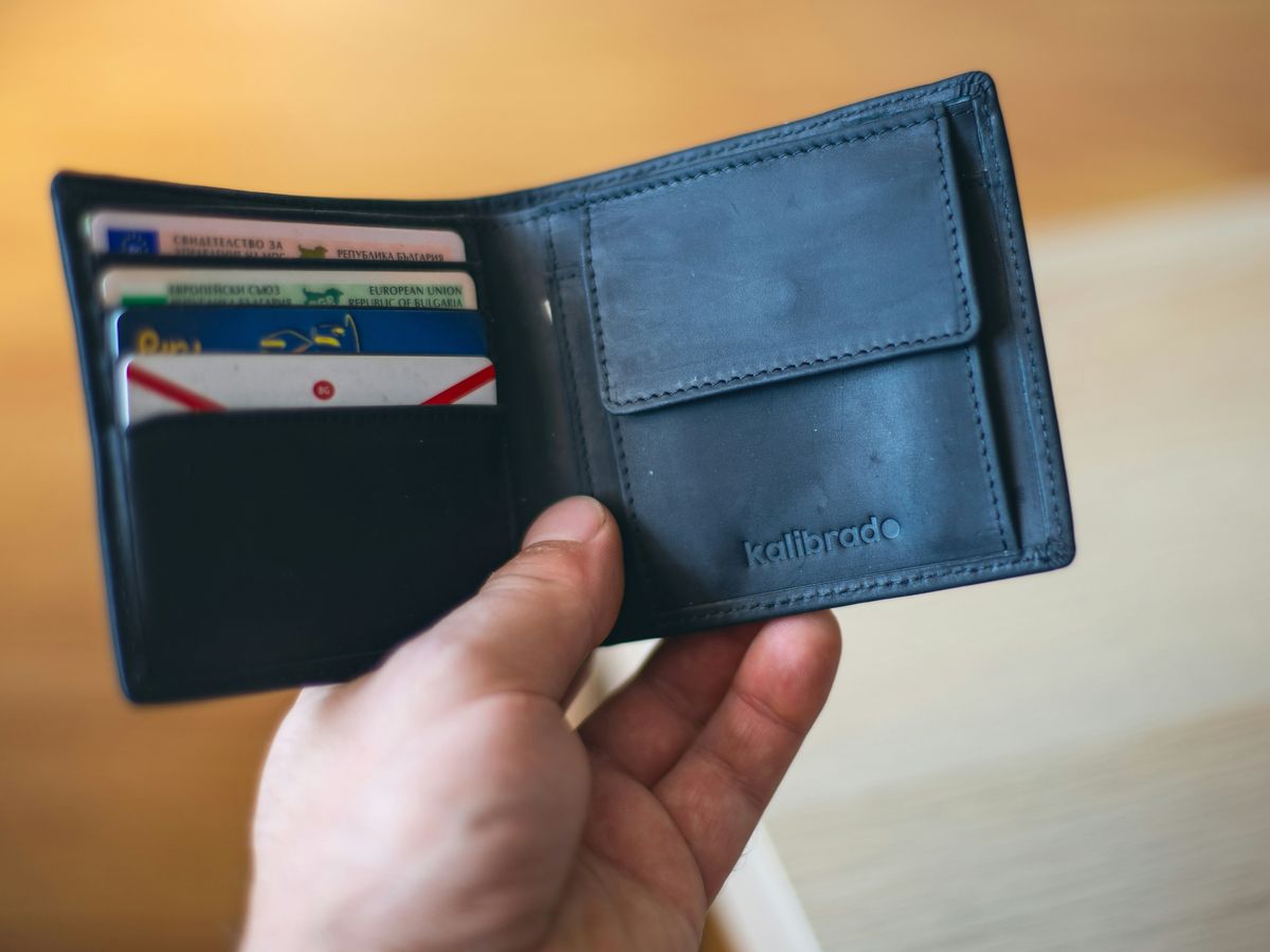 black leather bifold wallet on persons hand