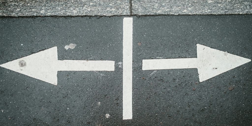 two white arrows pointing in opposite directions on asphalt