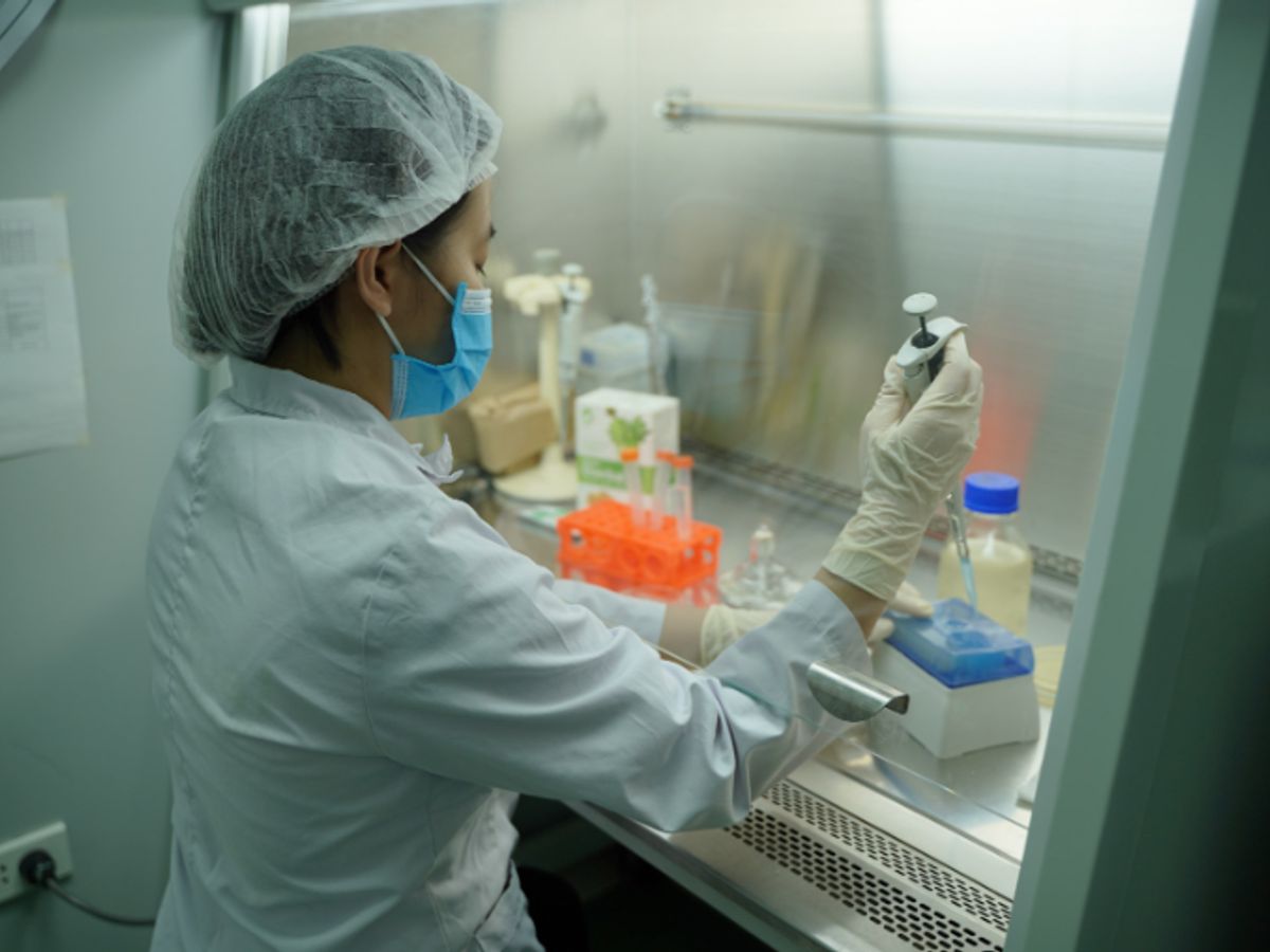 Scientist working in a lab with equipment and samples.