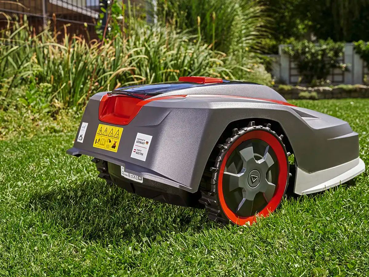Automated robotic lawn mower on green grass in garden.