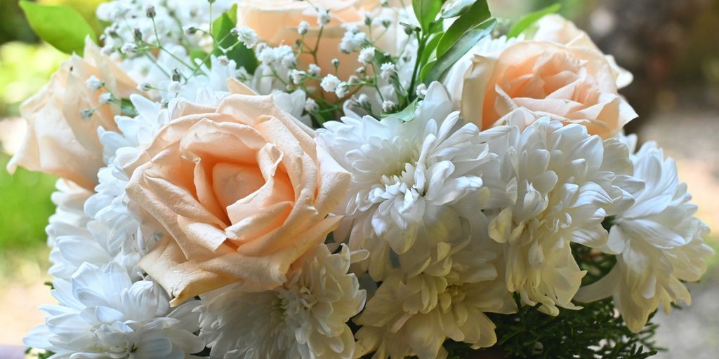 A bouquet of white and peach flowers in someone's hand