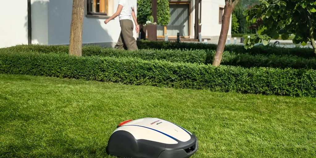 A robotic lawn mower operates in a landscaped yard.