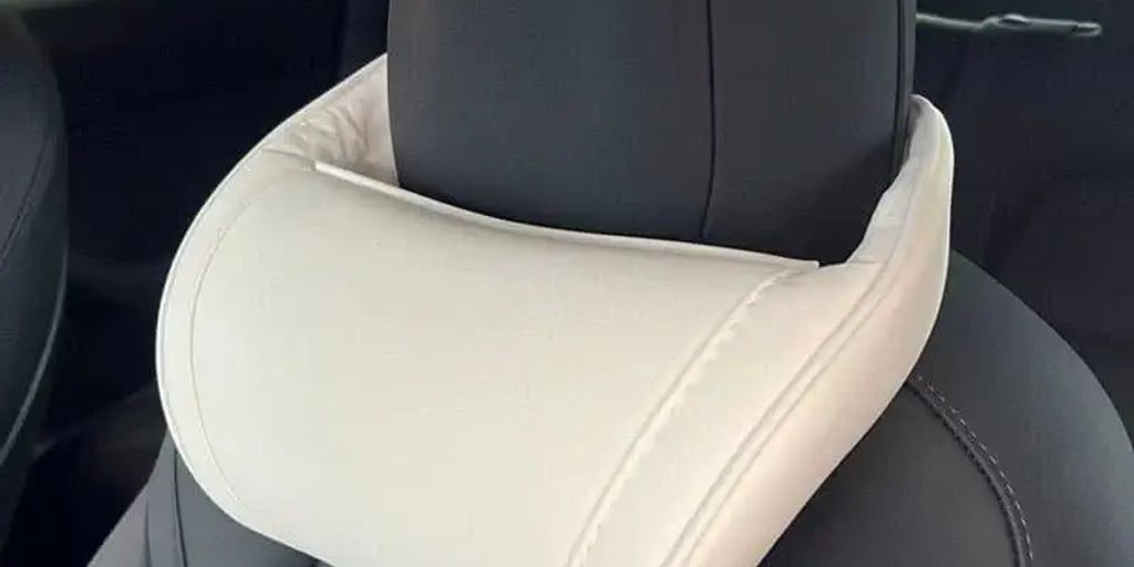 A white neck pillow attached to a car headrest.