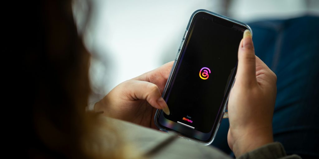 a woman holding a cell phone with a logo on it