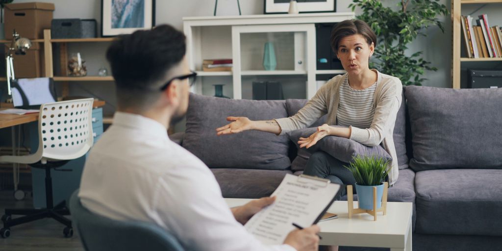a man sitting on a couch talking to a woman