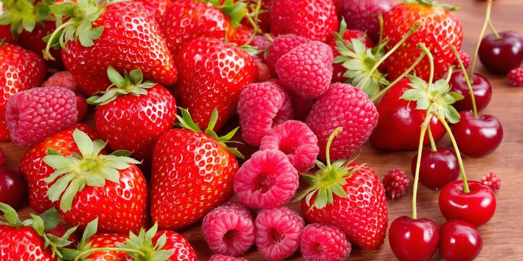 Descubra os 10 alimentos para baixar colesterol e melhorar sua saúde cardiovascular 3 Frutas vermelhas frescas sobre uma mesa de madeira.