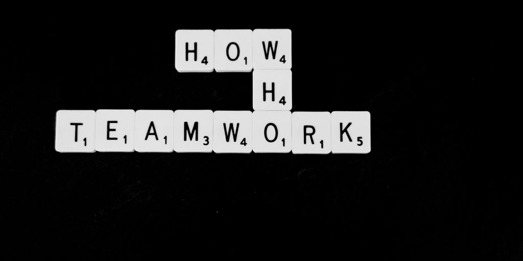a black and white photo of scrabble tiles spelling the word teamwork