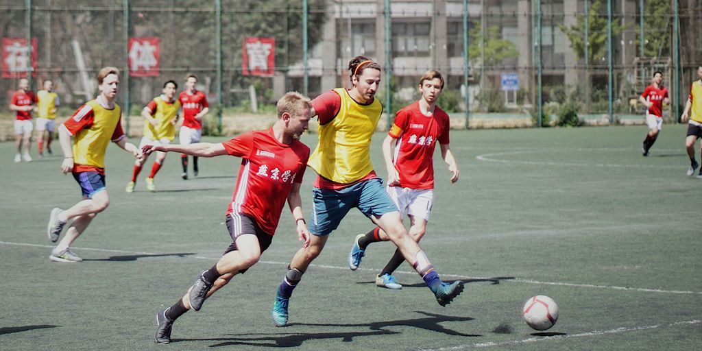 men playing soccer on field with fence