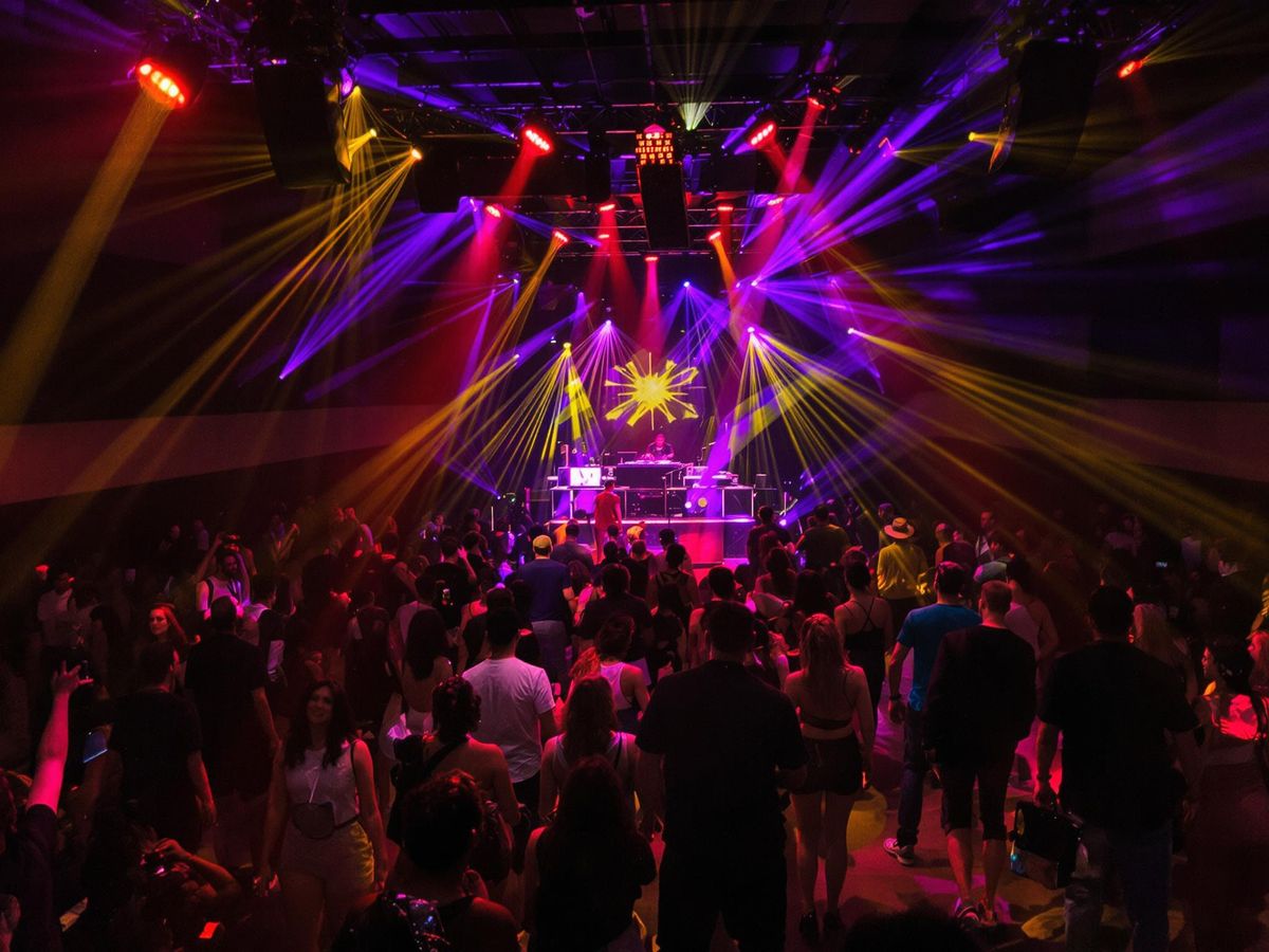 Energetic dancers on a vibrant dance floor under colorful lights.