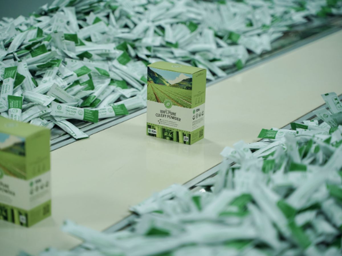 Packages of green powder mix scattered on a conveyor belt.