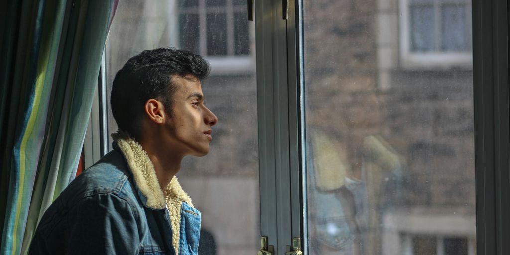 man in black jacket looking out the window