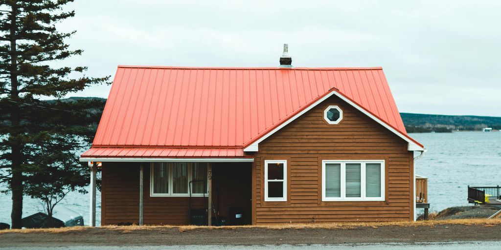 red and white wooden house near green trees under white clouds during daytime