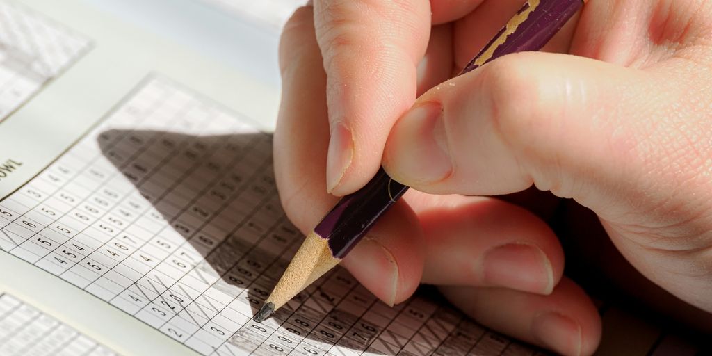 A person holding a pencil and writing on a piece of paper