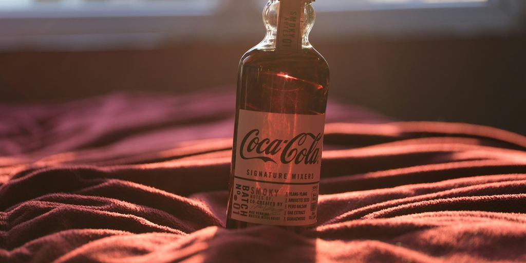 a bottle of coca cola sitting on top of a bed
