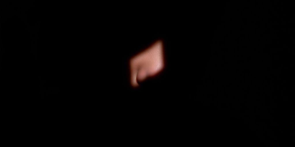 Person's downcast face, shadowed, looking away