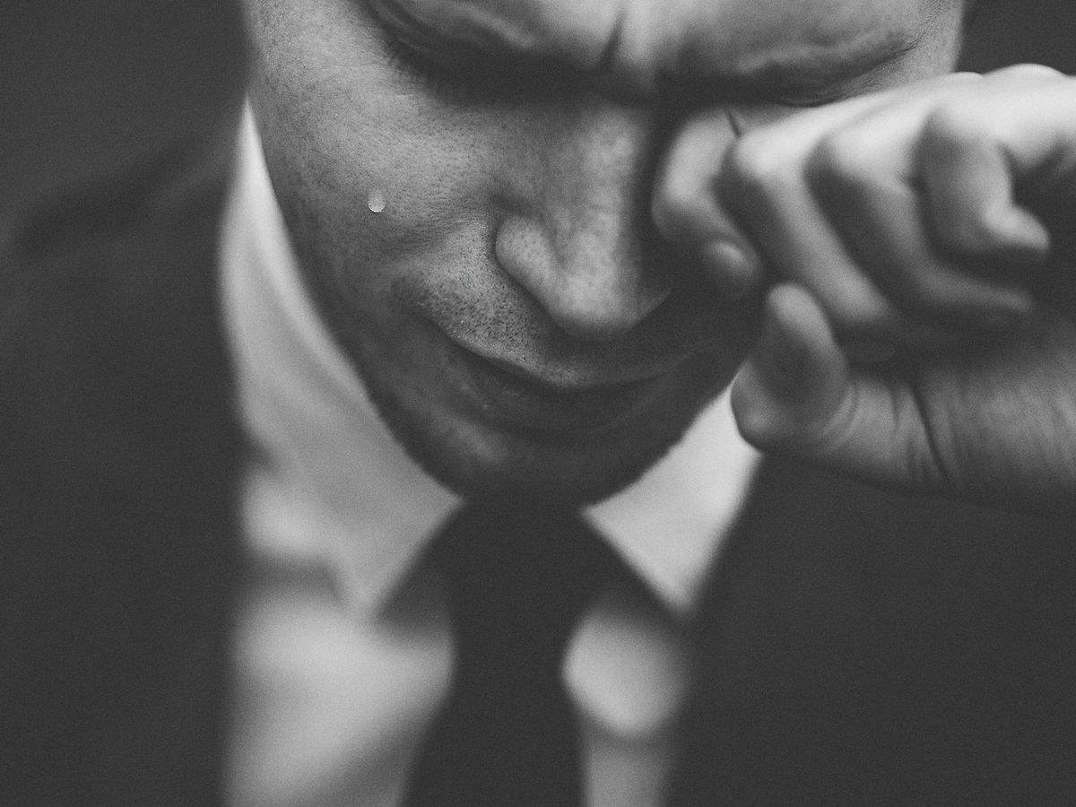 man wiping his tears
