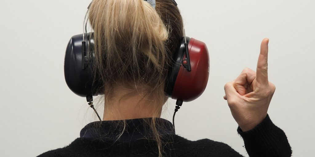 a woman wearing headphones pointing to the side