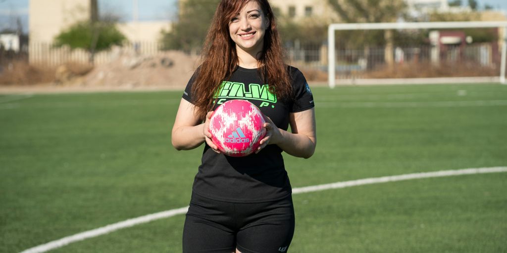 woman in black and pink nike soccer jersey shirt and black shorts holding pink ball