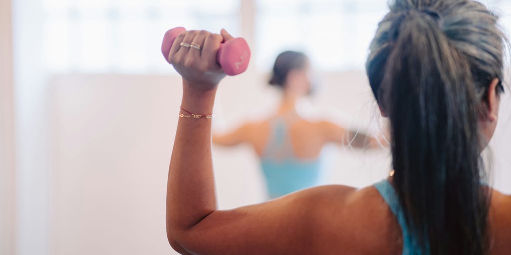 woman in blue tank top holding pink dumbbell