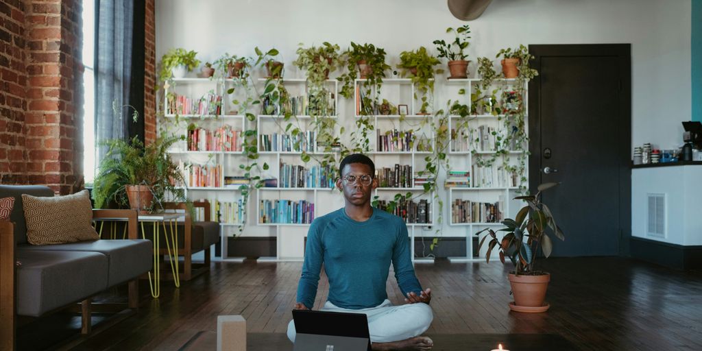 a man sitting on a yoga mat with a laptop in front of him