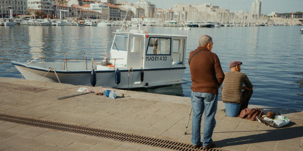 A man and a woman standing on a dock next to a boat