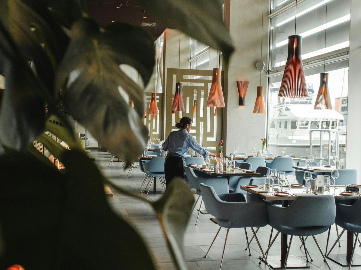 woman in front on brown dining table and chairs inside building