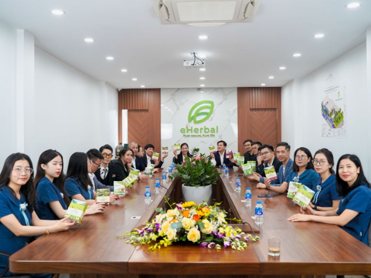 Group of people in a conference room discussing herbal products.