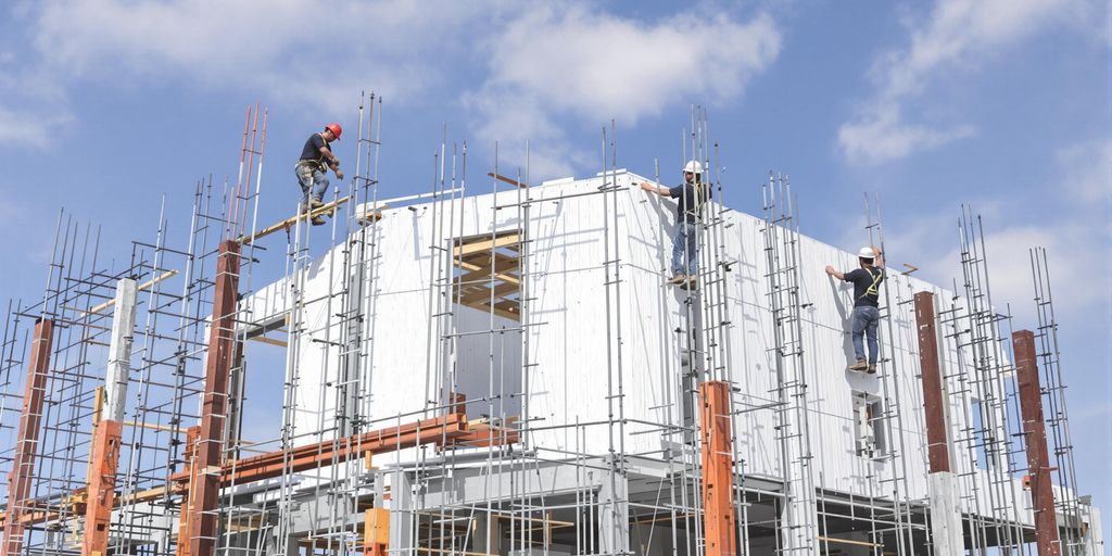 Workers installing PU sandwich panels at a construction site.