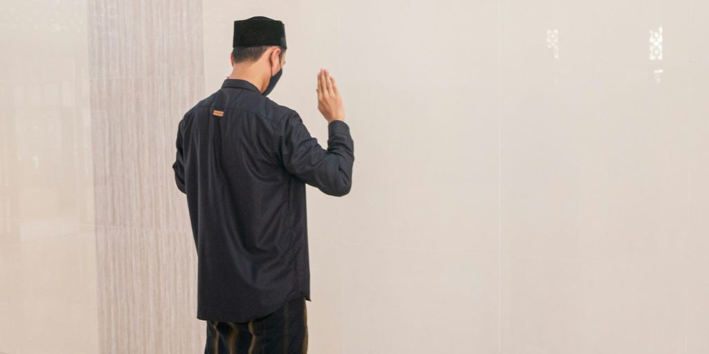 man in black jacket standing near white wall