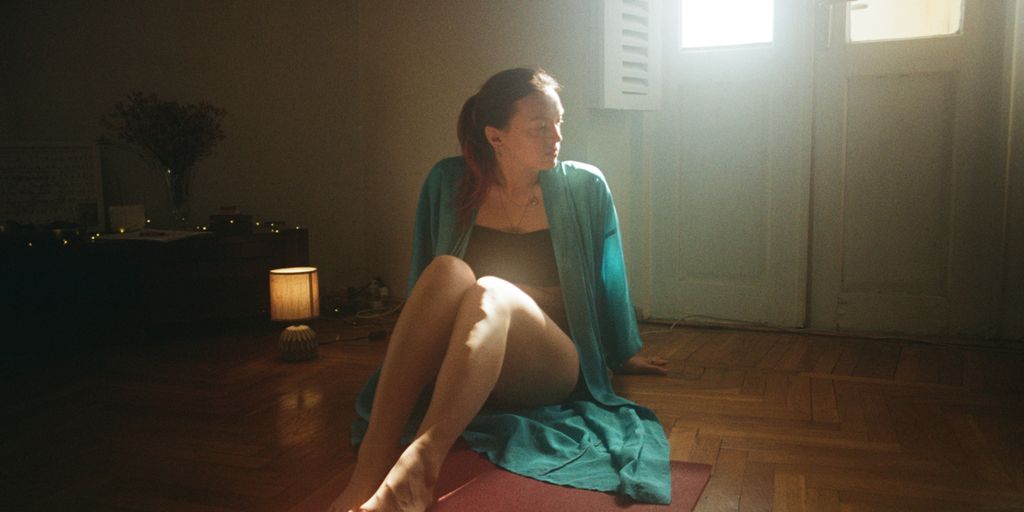A woman sitting on a yoga mat in a room