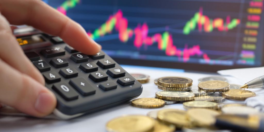 Hand with calculator, coins, and notepad for finance.