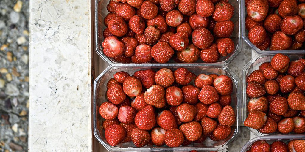 A bunch of strawberries are in plastic containers