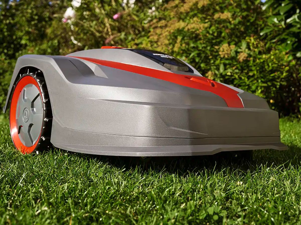 A robotic lawn mower on green grass in a garden.