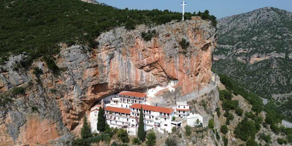 a white building on a cliff with a cross on top of it