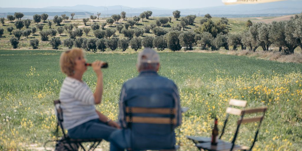 A man and a woman sitting on folding chairs in a field